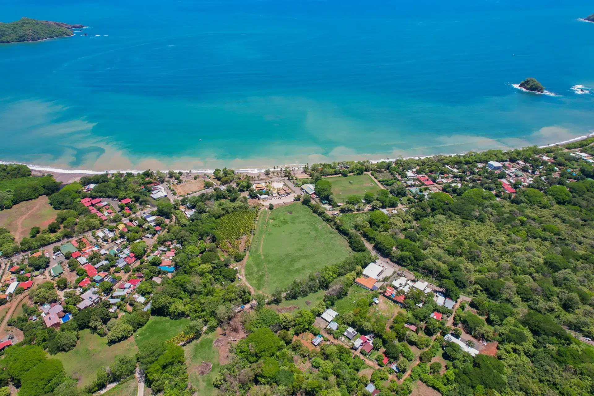 Vista aérea de un pueblo costero sobre una bahía turquesa